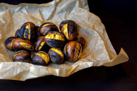 close up roasted chestnuts on paper and black stone background .の写真素材