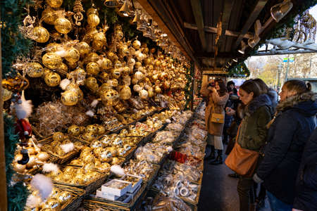 Vienna, Austria - 11.23.2019 : young women tourists admiring hanging golden Christmas ornament decoration kiosk stand on a winter market rathausplatz .のeditorial素材