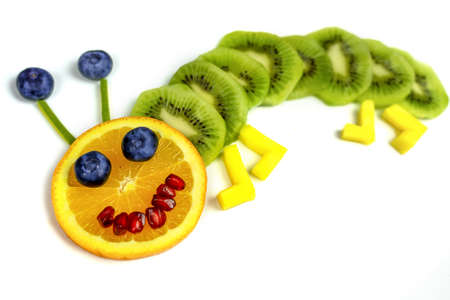 funny fruit worm on white plate healthy dessert for kids .の写真素材