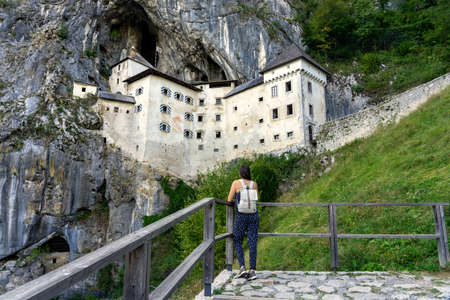 predjama castle built into a mountain in the nature near to postojna cave with a tourist woman watching itの写真素材