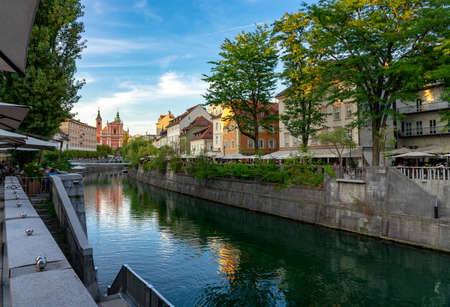 Ljubljana city center Tromostovje bridge on Ljubljanica river in Slovenia Ljubjana with Cerkev Marijinega oznanjenja church with river bankの写真素材