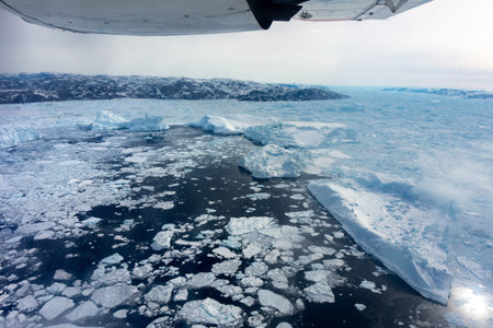 flying tour above Greenland with Icebergs floating on the ocean