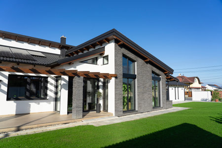 Modern house with gray stone wall and white walls in a garden witg fresh green grasの写真素材