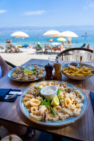 eating fried squid calamari with a sea view from the beach bar in croatiaの写真素材