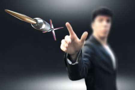 business man thowing dart to a objective darts board in a blurred backgroundの写真素材