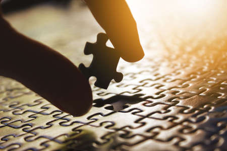 Fingers putting the last piece of a puzzle metaphor. Incomplete, integration, buildの写真素材
