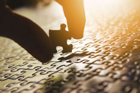 Man putting the last piece of a puzzle metaphor. Incomplete, integration, buildの写真素材
