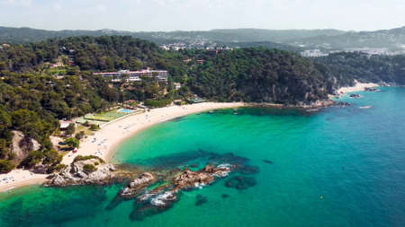 Beautiful aerial view of beach with ferry boat and resort in Cala Santa Cristina, Blanes, Costa Brava, Spainの写真素材