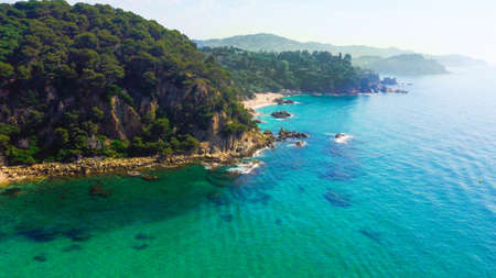 Beautiful aerial view of beach with ferry boat and resort in Cala Santa Cristina, Blanes, Costa Brava, Spainの写真素材