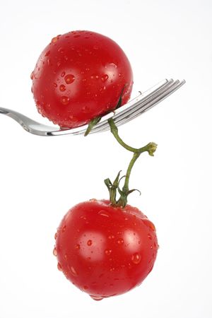 two tomatoes dangling from a forkの写真素材