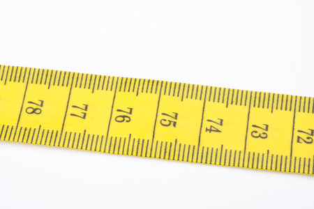 yellow measuring tape used by tailors on white