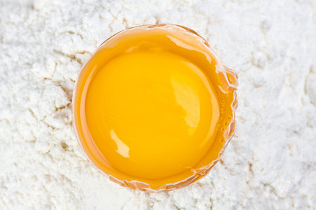 open egg on a bed of flourの写真素材
