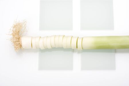 slices of leek on a glass chopping boardの写真素材