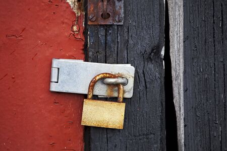 rusty old padlock on a wooden doorの写真素材