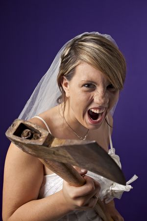 angry young bride with an axe on a dark blue backgroundの写真素材