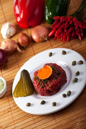 steak tartar with an onion ring and an open eggの写真素材