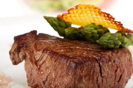 closeup of a beef steak with green asparagus on a white backgroundの写真素材