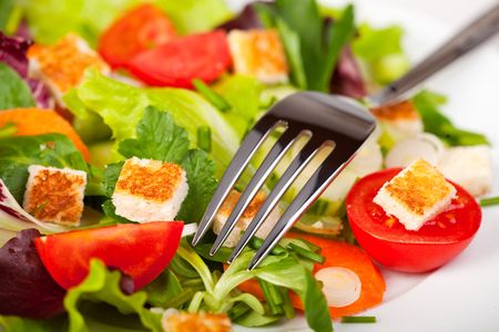 mixed salad on a white plate with a forkの写真素材