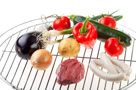 raw meat, sausages and vegetables on a gridironの写真素材
