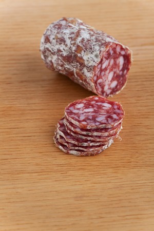 slices of an a italian salami on an oak tableの写真素材