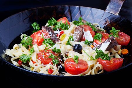 fresh pasta with tomatos and olives in a panの写真素材
