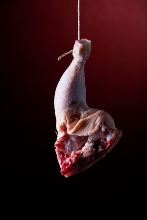 hanging chicken leg on redの写真素材