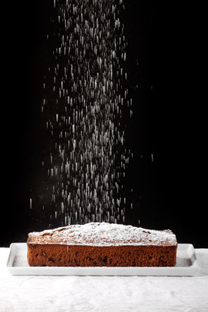icing sugar falling on a chocolate cake 