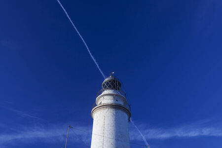 lighthouse with contrail の写真素材