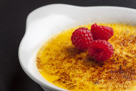 closeup of a creme brule with raspberriesの写真素材