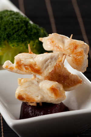 grilled chicken meat on a skewer with chop sticksの写真素材
