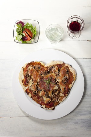 heart shaped pizza on white wood の写真素材