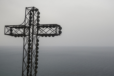 metal cross overlooking the sea in the dusk の写真素材