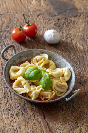 tortellini on wood with tomato sauceの写真素材