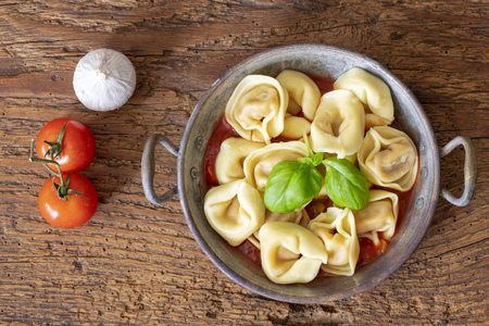 tortellini on wood with tomato sauceの写真素材