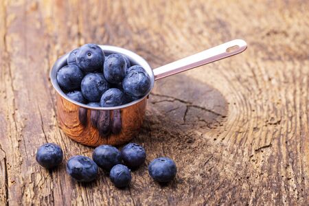 blue berries in a pot on woodの写真素材