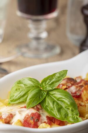 pasta gratin on wood with basilの写真素材