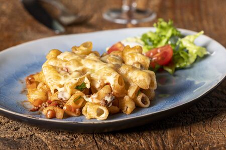 portion of a pasta gratin on wood の写真素材