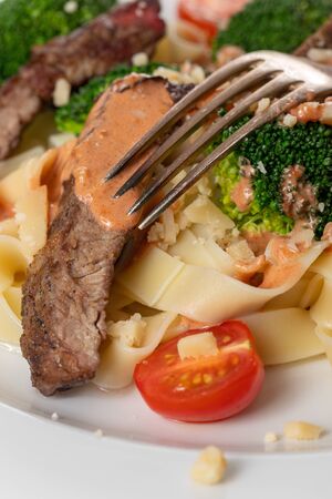 tagliatelli with steak slices on a plate の写真素材