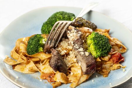 tagliatelli with steak slices on a plate の写真素材