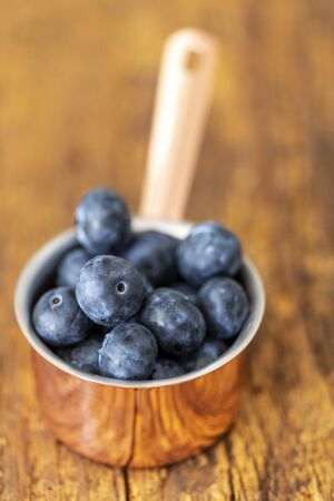 blue berries in a pot on woodの写真素材