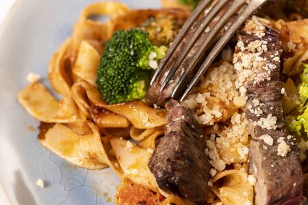tagliatelli with steak slices on a plateの写真素材