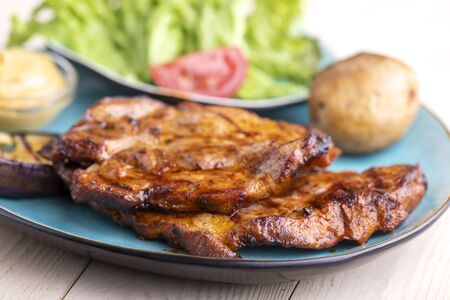 grilled pork steaks on a blue plateの写真素材