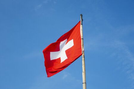 swiss flag on a pole on a sunny dayの写真素材