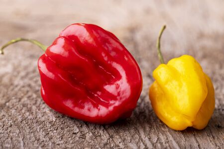 red and yellow habanero chili on woodの写真素材