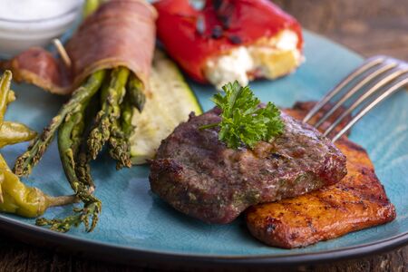 grilled meat and green asparagus on a blue plateの写真素材