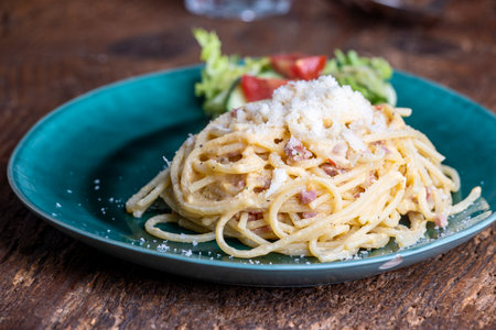 Spaghetti carbonara on a green plateの写真素材