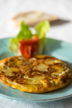 tortilla espanola on a plate with tomatoの写真素材