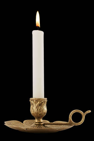 Brass Candleholder - Decorative antique brass candelabra with brightly lit white pillar candle.  Isolated over black.の写真素材