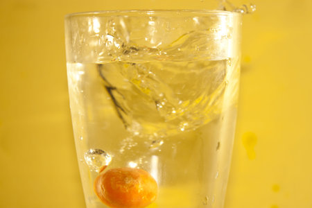 Water splash in glass isolated on orange background.