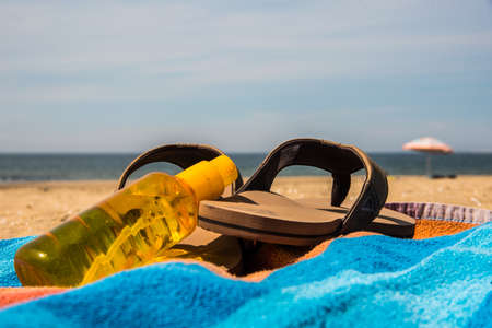 Den Helder, the Netherlands, June 3, 2021. Close up of flip-flops, sunscreen and a colorful towel at the beach of Huisduinen, the Netherlands. High quality photo. Close upの写真素材